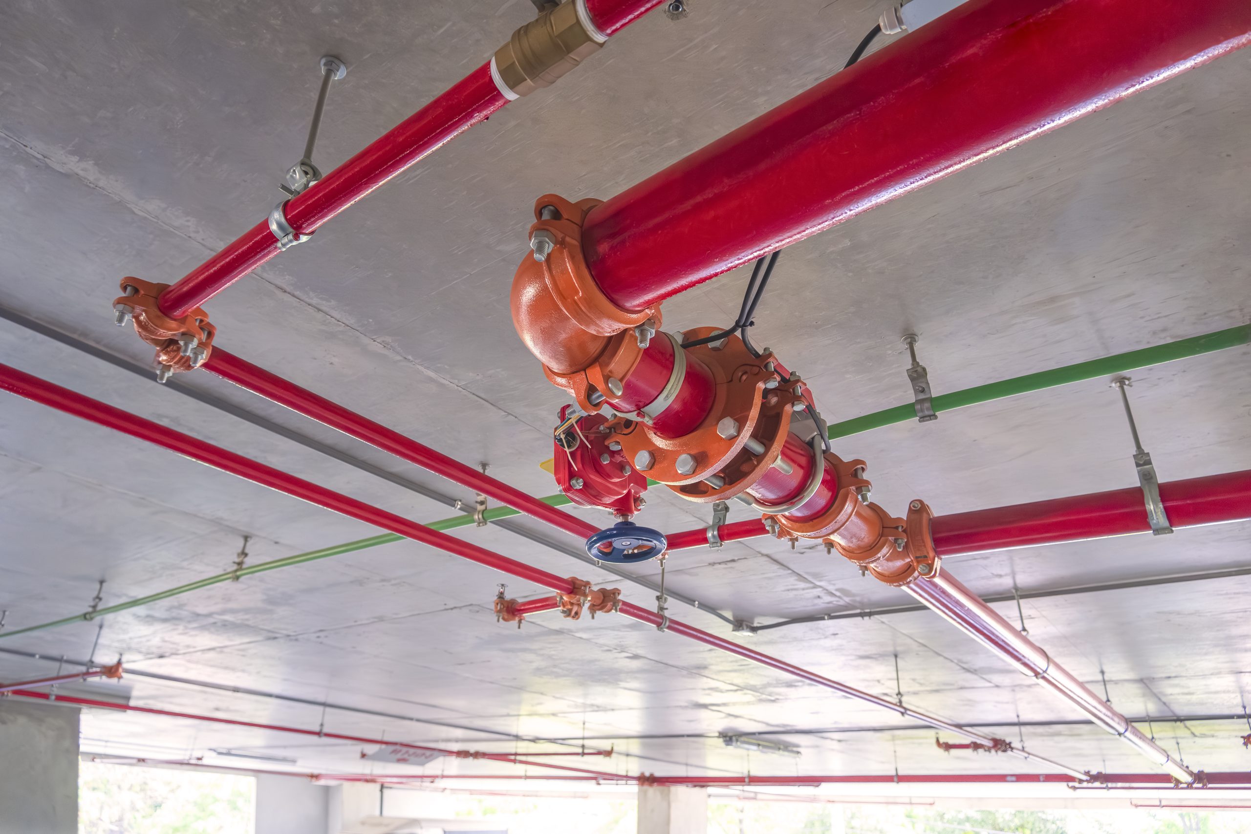 Red fire protective water pipeline system mounted along an exterior building wall
